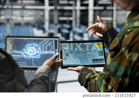 Team of army workers in data center mapping airborne activity using predictive AI tech on devices. Military units in server room flagging unusual movement using deep learning detection tools on tablet 131615927