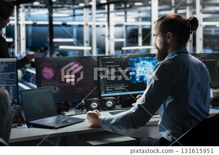 Frustrated data center system administrator at desk upset by malfunctioning gear while using AI. Upset server room IT worker disgruntled by errors in glitching artificial intelligence software 131615951