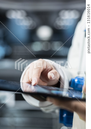 Close up of astronaut checking orbital navigation data on tablet to ensure safe operation during long distance space travel. Orbital station crew member runs telemetry software during cosmic journey 131616014
