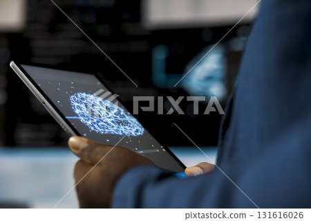 Young professional engineer focused on coding with tablet at an innovation hub, using programming language on terminal window for automation. Tech career in data science. Close up. Young professional engineer focused on coding with tablet at an innovation hub, using programming language on terminal window for automation. Tech career in data science. Close up. 131616026