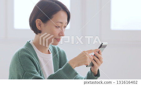 A woman in a knitted sweater looking at her smartphone A woman in a knitted sweater looking at her smartphone 131616402