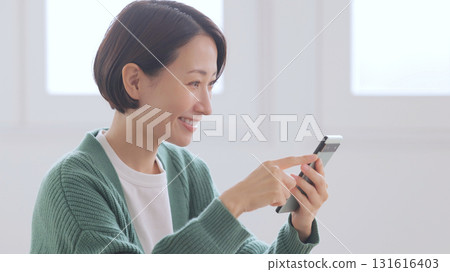 一位身穿針織毛衣的女士正在看她的智慧型手機 一位身穿針織毛衣的女士正在看她的智慧型手機 131616403