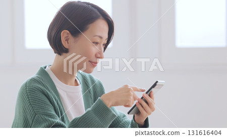 一位身穿針織毛衣的女士正在看她的智慧型手機 一位身穿針織毛衣的女士正在看她的智慧型手機 131616404