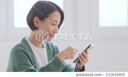 一位身穿針織毛衣的女士正在看她的智慧型手機 一位身穿針織毛衣的女士正在看她的智慧型手機 131616405