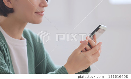 A woman in a knitted sweater looking at her smartphone 131616408