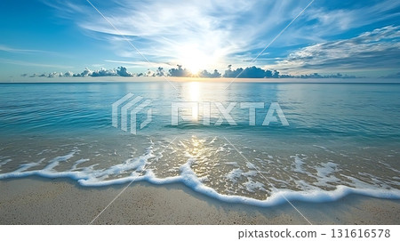 Serene Sunrise Over Calm Ocean Waves with Soft Sandy Beach and Bright Blue Sky 131616578