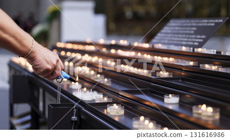 Lighting candles in a quiet memorial space for reflection and remembrance during a peaceful moment Lighting candles in a quiet memorial space for reflection and remembrance during a peaceful moment 131616986