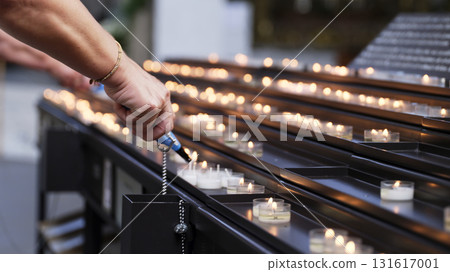 People lighting candles in a quiet space during a reflective moment in a serene setting 131617001