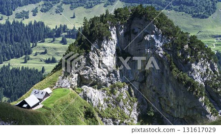 Scenic mountain view with a solitary cabin nestled near a rugged cliff in the Swiss Alps landscape 131617029