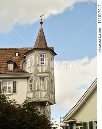 Beautiful old building with a pointed tower in a quaint European town under a blue sky Beautiful old building with a pointed tower in a quaint European town under a blue sky 131617041