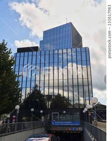 Modern office building with reflective glass facade under a cloudy sky in a city center Modern office building with reflective glass facade under a cloudy sky in a city center 131617063