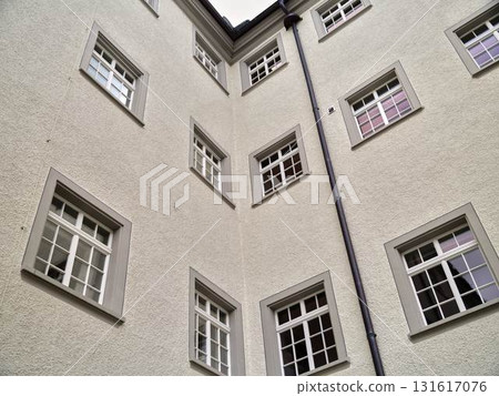 Multiple windows of a historical building juxtaposed against a cloudy sky in a quiet urban neighborhood 131617076