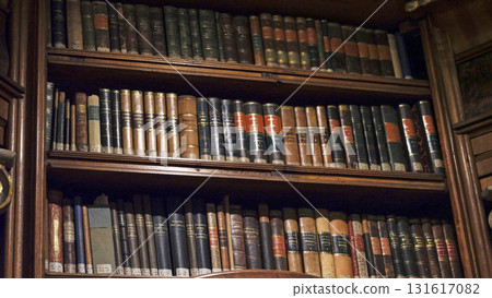 Vintage library shelves filled with classic literature and leather-bound books in a cozy reading nook 131617082