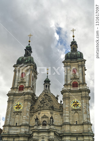 Historic church towers under cloudy sky with golden clock faces in Switzerland 131617097