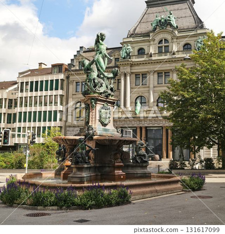 Elegant fountain and historic architecture in a bustling urban square during a sunny day 131617099