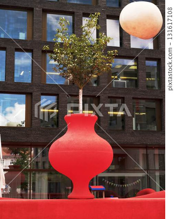 Creative red planter with a tree in an urban setting showcasing modern architecture and outdoor design elements 131617108