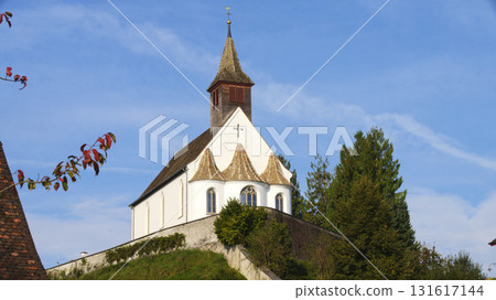 Beautiful church on a hill beneath a clear blue sky surrounded by trees during the daytime 131617144