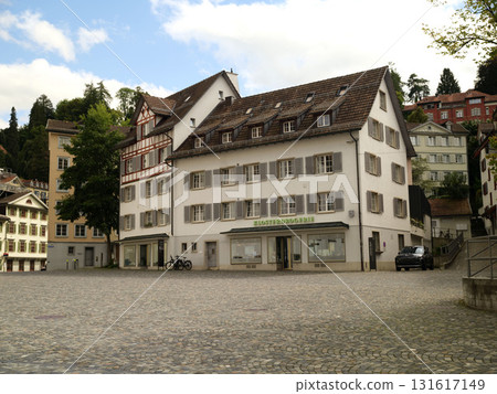 Historic buildings and cobblestone square in a charming Swiss town during the day Historic buildings and cobblestone square in a charming Swiss town during the day 131617149