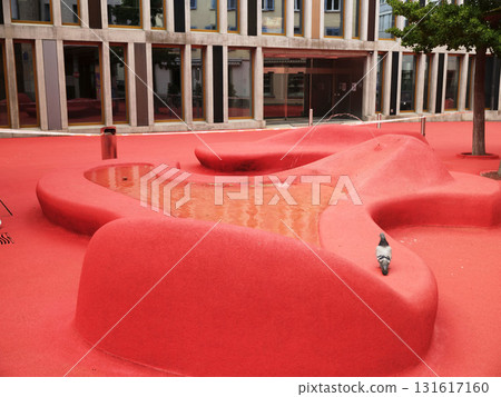 Unique red landscape with pond and art structures in an urban park setting on a sunny day Unique red landscape with pond and art structures in an urban park setting on a sunny day 131617160
