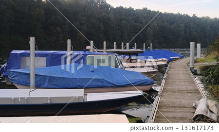 Docked boats covered with blue tarps at a peaceful marina in early morning light Docked boats covered with blue tarps at a peaceful marina in early morning light 131617173