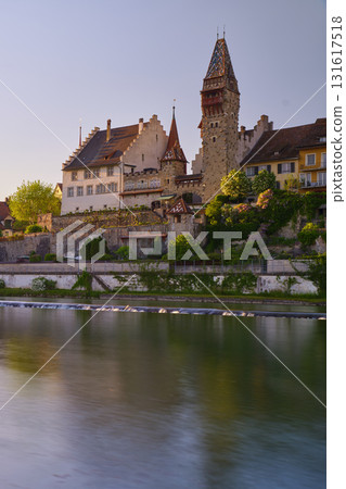 Historic castle and tower overlook tranquil river at sunset in a charming European town Historic castle and tower overlook tranquil river at sunset in a charming European town 131617518