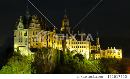 Illuminated German castle on a hilltop against the night sky showcasing intricate architecture and historical significance 131617530