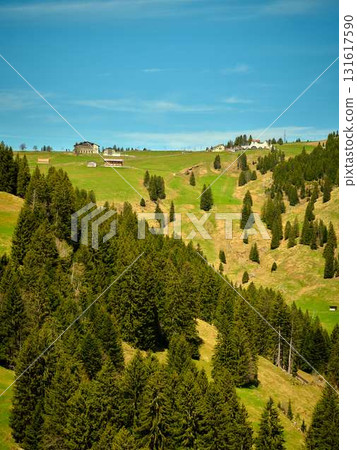 Serene alpine landscape with lush green hills and rustic cabins on a sunny day Serene alpine landscape with lush green hills and rustic cabins on a sunny day 131617590
