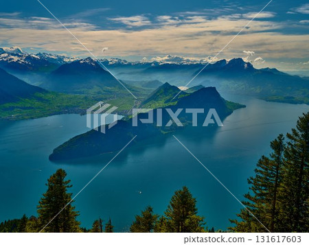 Panoramic view of a tranquil lake surrounded by mountains and lush forests in Switzerland on a clear day 131617603