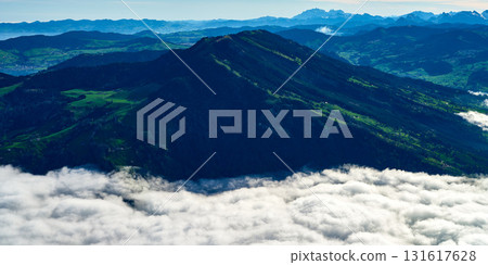 Scenic mountain view above clouds with green valleys and distant peaks in clear weather 131617628