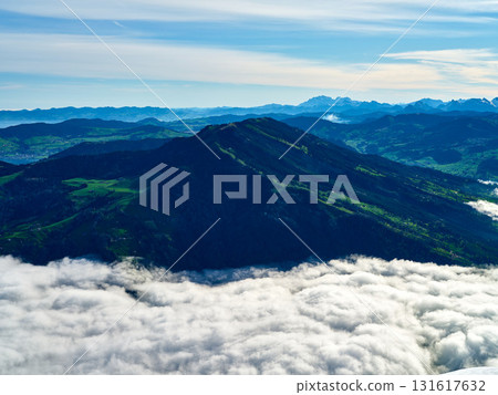 Mountain peak rises above clouds in bright daylight with distant hills and valleys in the background 131617632