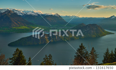 Mountain lake with island view and snow-capped peaks during golden hour in Switzerland 131617650