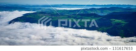 Clouds blanket the valley as green hills rise dramatically against a clear blue sky 131617653