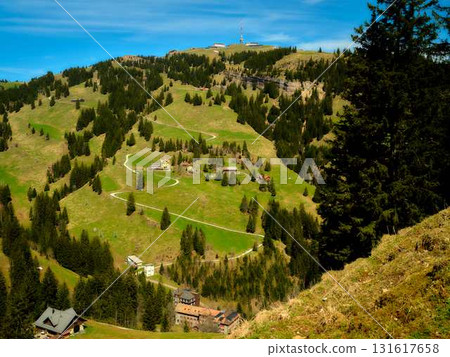 Mountain landscape view showing lush green hills, scattered houses, and a serene sky on a bright sunny day in the Swiss Alps Mountain landscape view showing lush green hills, scattered houses, and a serene sky on a bright sunny day in the Swiss Alps 131617658