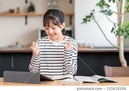 Elementary school and junior high school girls studying using a tablet and making a fist pump Elementary school and junior high school girls studying using a tablet and making a fist pump 131618109