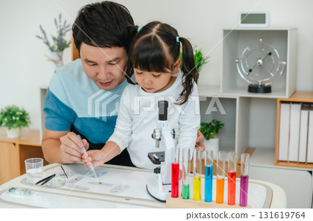 toddler girl scientist using pipette dropping of liquid being placed on glass slide with her father, preparing specimen for science microscope toddler girl scientist using pipette dropping of liquid being placed on glass slide with her father, preparing specimen for science microscope 131619764
