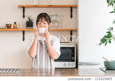 Elementary school and junior high school girls wearing aprons drinking hot drinks in the kitchen Elementary school and junior high school girls wearing aprons drinking hot drinks in the kitchen 131620065