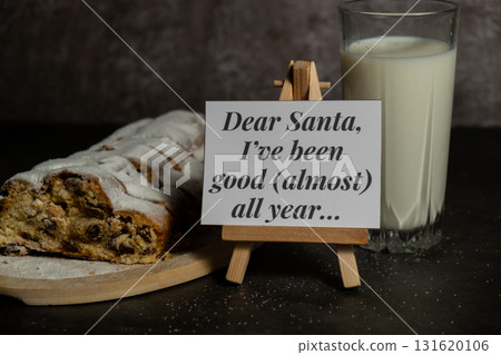 Paper note with text DEAR SANTA I HAVE BEEN GOOD ALMOST ALL YEAR joke humor pun.Christmas Stollen with glass of milk for SANTA in Christmas lights and decoration. Traditional sweet fruit loaf with Paper note with text DEAR SANTA I HAVE BEEN GOOD ALMOST ALL YEAR joke humor pun.Christmas Stollen with glass of milk for SANTA in Christmas lights and decoration. Traditional sweet fruit loaf with 131620106