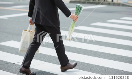 business man walking_A businessman crossing the crosswalk with a green onion 131620238