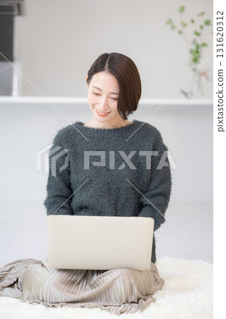 面帶微笑的女士正在電腦上搜尋。圖片為在家線上學習。圖片為秋冬針織品。向下看。 131620312