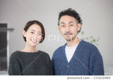 A couple in their 40s relaxing in a bright living room, looking at the camera. A new home and lifestyle image for autumn and winter. A couple in their 40s relaxing in a bright living room, looking at the camera. A new home and lifestyle image for autumn and winter. 131620460