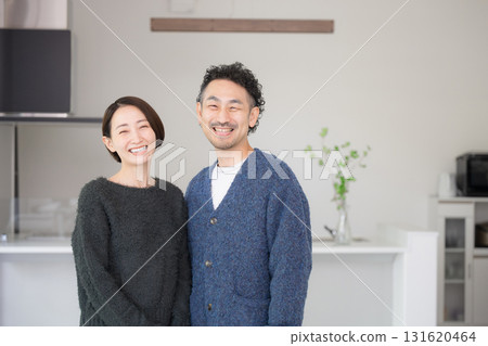 一對四十多歲的夫婦在明亮的客廳放鬆，看著鏡頭。新家，新生活方式。秋冬。 131620464