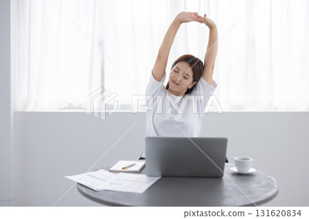 A woman stretching and refreshing while working on a computer A woman stretching and refreshing while working on a computer 131620834