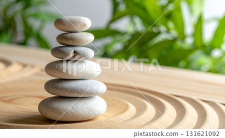 Smooth gray zen stones stacked for balance and harmony on a wooden table 131621092