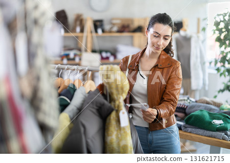 Female shopper selects clothes for autumn winter season in clothing store Female shopper selects clothes for autumn winter season in clothing store 131621715