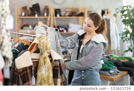 Young woman near showcase examine goods, buying down jacket. 131621716