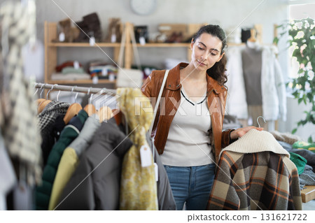 Armenian woman near showcase examine goods, buying checkered jacket 131621722
