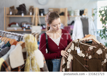 Young woman chooses cardigan in clothing store 131621723