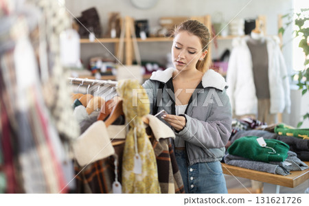 Young woman standing near hangers in store 131621726