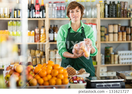 Adult woman seller offers tangerines in grocery store 131621727