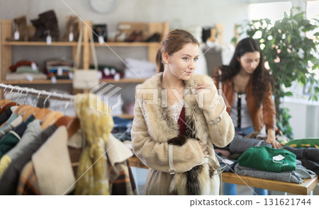 Young woman trying on fur coat in store Young woman trying on fur coat in store 131621744